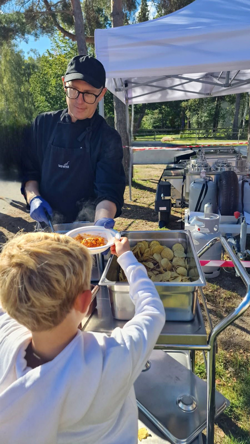 Kökspersonal serverar barn utomhus.