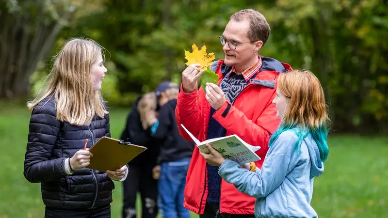 En lärare visar ett löv för elever utomhus