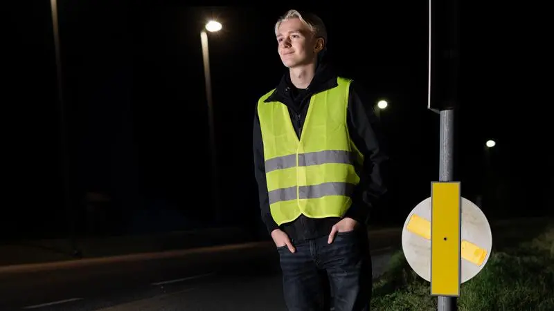En ung man som står bredvid en reflexsnurra på natten.