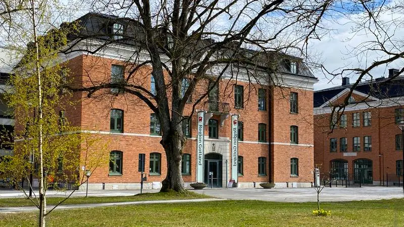 Rådhuset i Visby, rött tegelhus med fyra våningar med en grön park framför