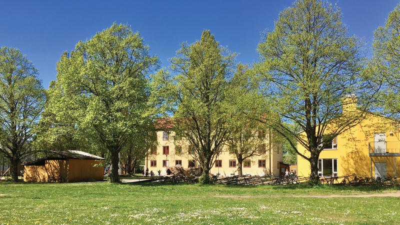 Ett stort gult hus som ligger vid ett  fält.
