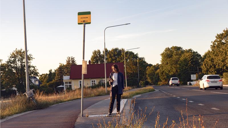 En kvinna som står vid en busshållplats.