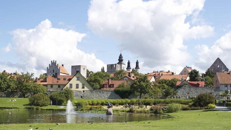 En park med en damm och byggnader i bakgrunden.