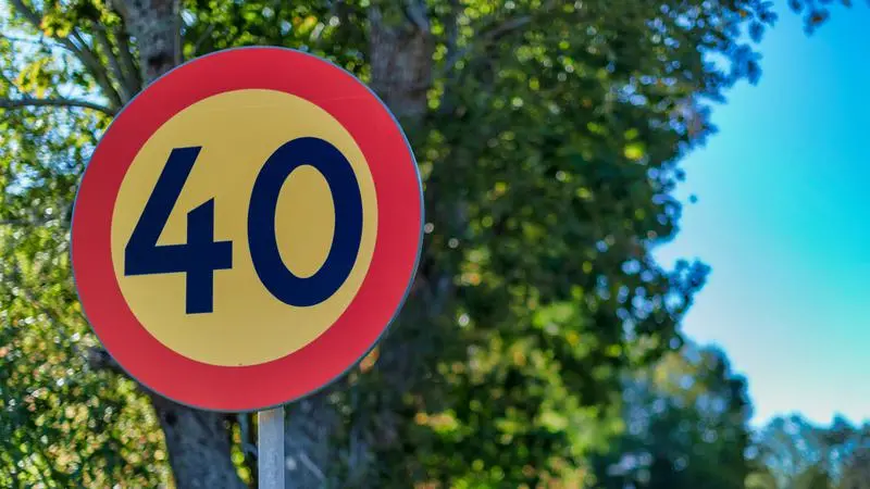 Hastighetsskylt 40 km/h intill ett träd.