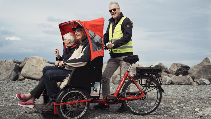 tre äldre personer på en cykel