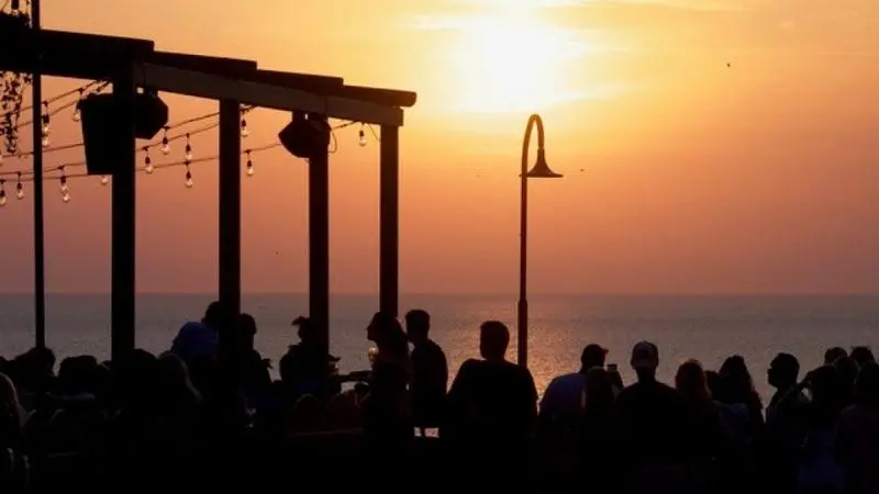 En grupp människor som står på toppen av en strand intill havet.
