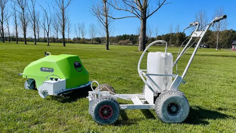 En grön och en vit robot på en gräsplan.
