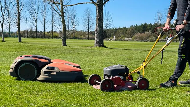 Två olika sorters gräsklippare på en gräsplan.