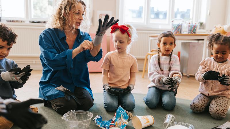 Pedagog och barn på förskola sätter på sig handskar.