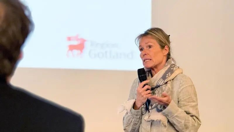 Kvinna med mikrofon framför en presentationsbild