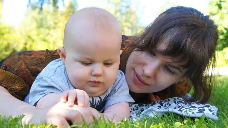 Mamma och barn leker i gräset