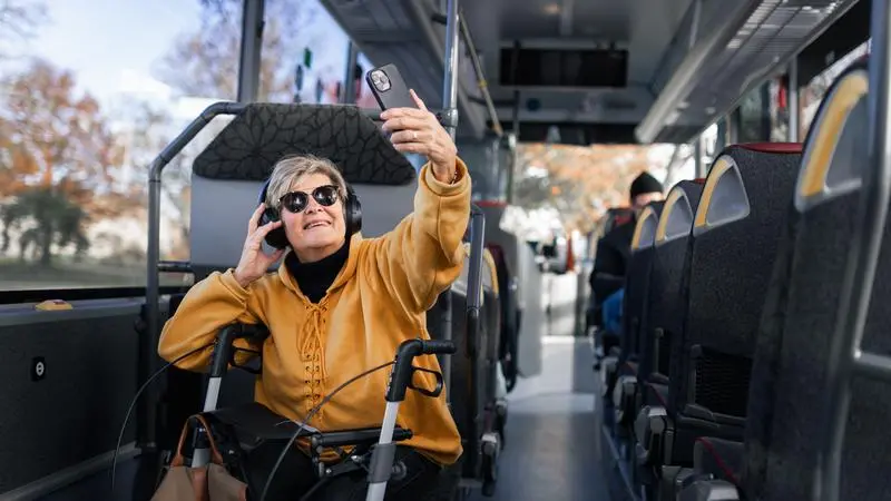 En kvinna sitter på en buss och tar en selfie
