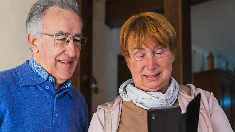 Äldre par som tittar i en mobiltelefon.