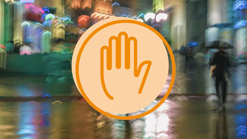 En orange hand i en cirkel på en bild med ljus från stadsmiljö.