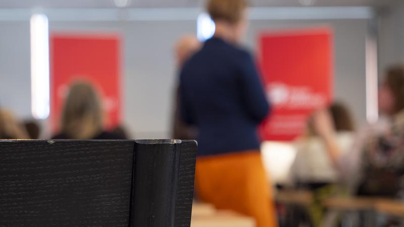 Närbild på en stol med människor i möte i bakgrunden