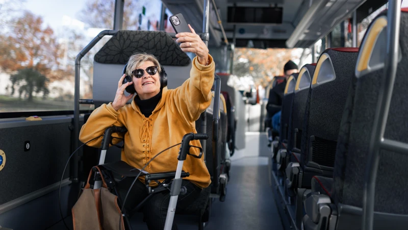 En kvinna sitter på en buss och tar en selfie
