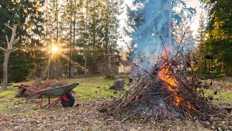 En skottkärra bredvid en brinnande rishög