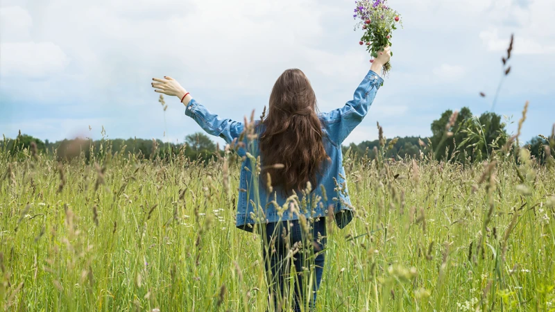 En kvinna står på ett fält och håller i en blombukett