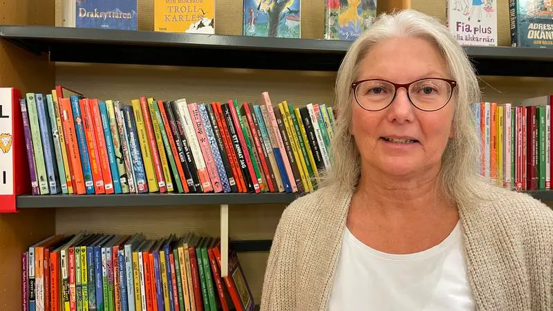 Kvinna som står framför bokhylla i bibliotek