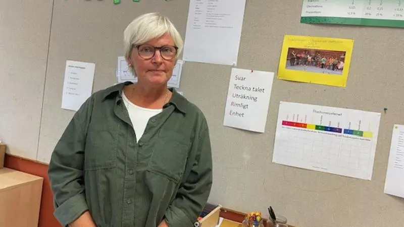 Kvinna som står framför en anslagstavla i skolmiljö