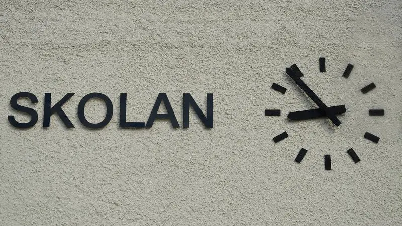 Vägg där det står skolan med en klocka brevid