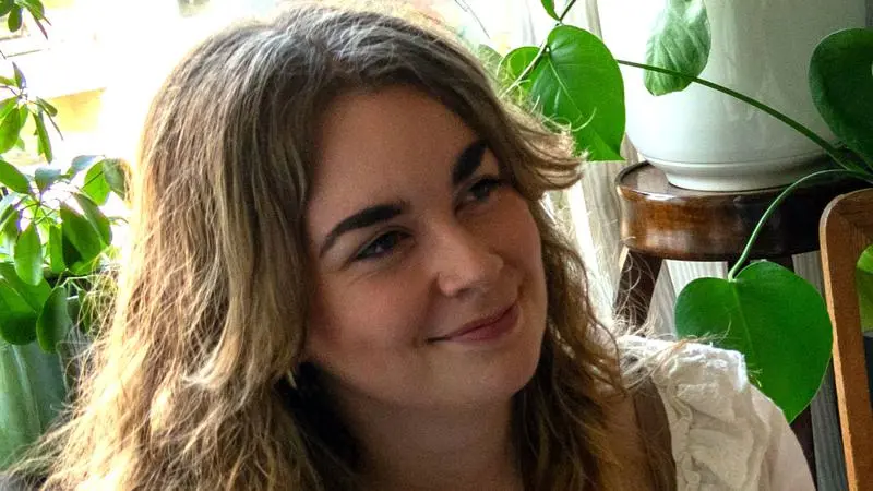 Vilma Hult sitter intill gröna växter.