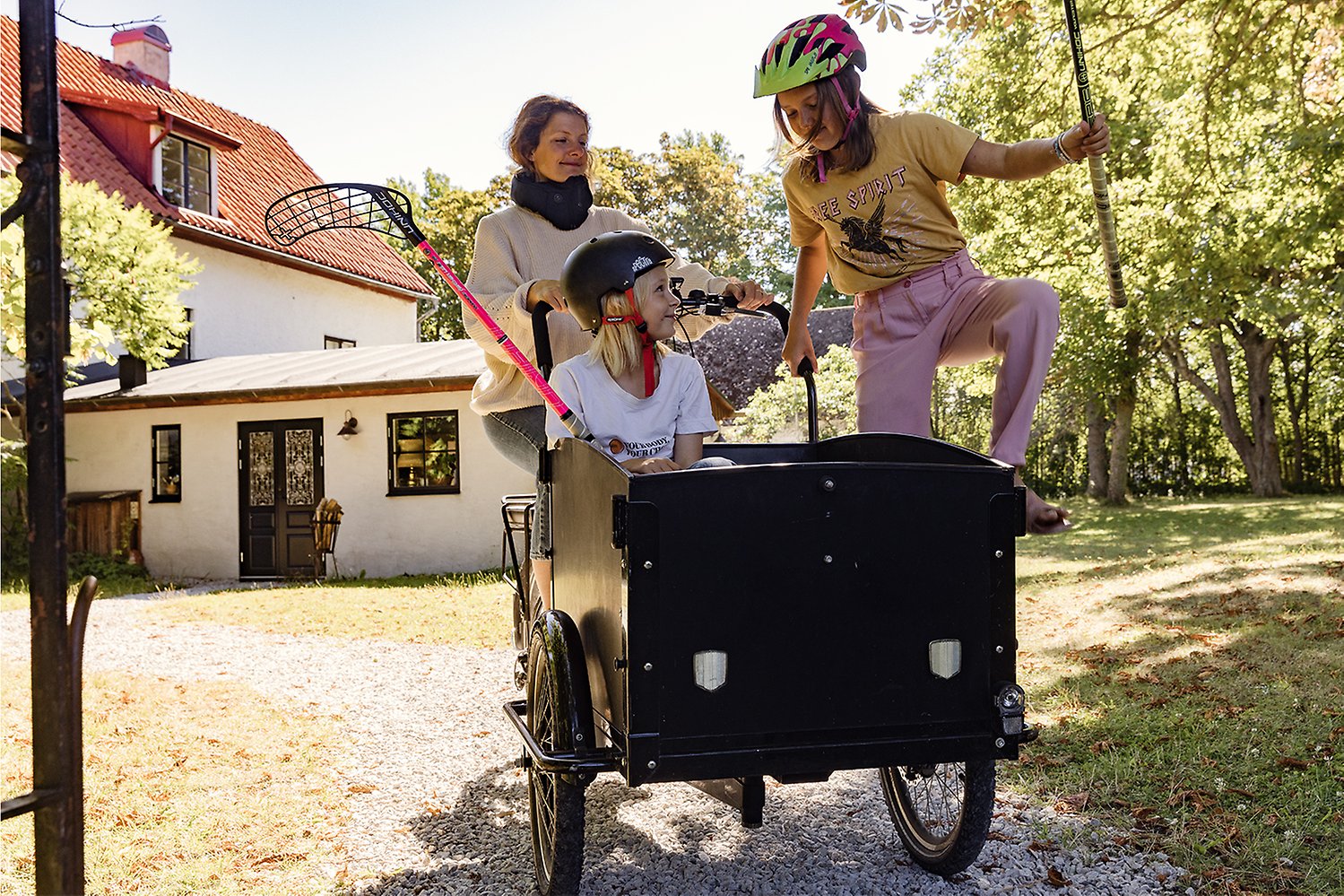 En kvinna med en lådcykel där i två barn sitter