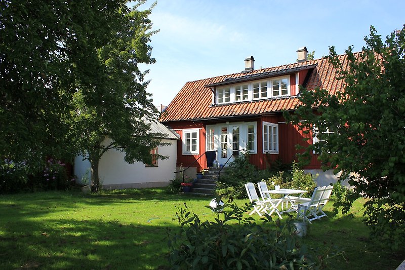 Ett rött hus med en träfasad, vita fönster och ett rött tegeltak.