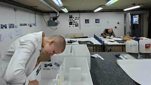 Två människor jobbar intensivt med papper och modeller