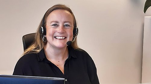 Kvinna sitter vid dator och ler