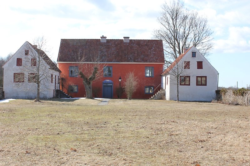 Två vita hus med röda fönster och röda tak, samt ett rött hus med blåa fönster och ett rött tak.