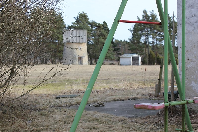 En kvarn och en liten vit bod finns nära ett skogsområde.
