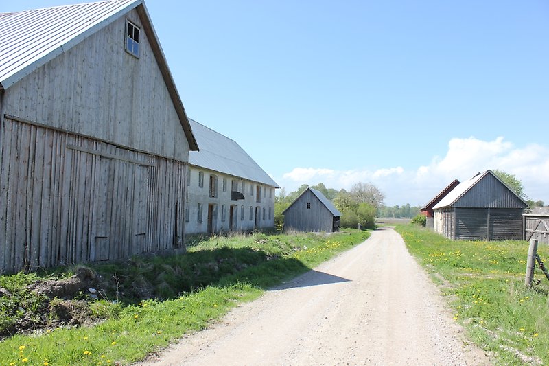 En liten bebyggelse av flera träbyggnader och en vit lada med ett plåttak.