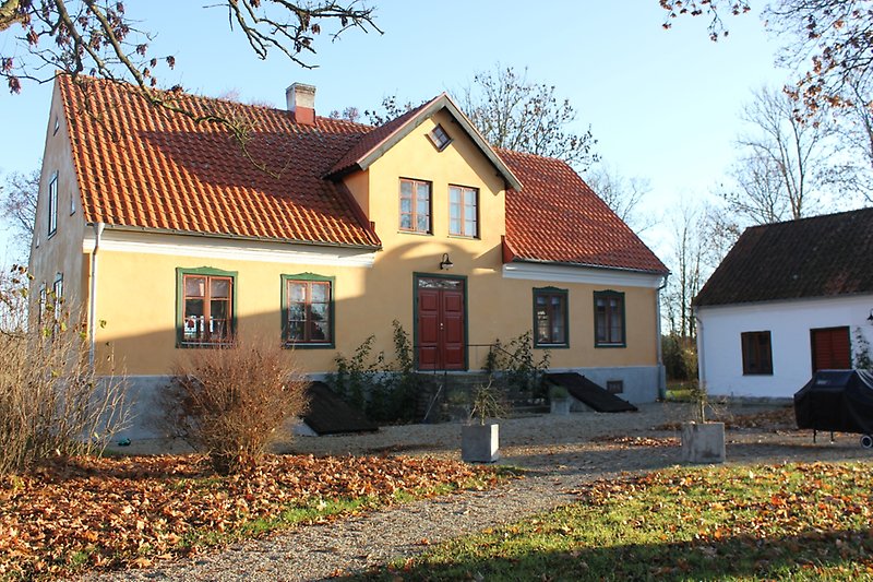 Ett gult hus med bruna fönster, bruna dörrar och ett orange tak.