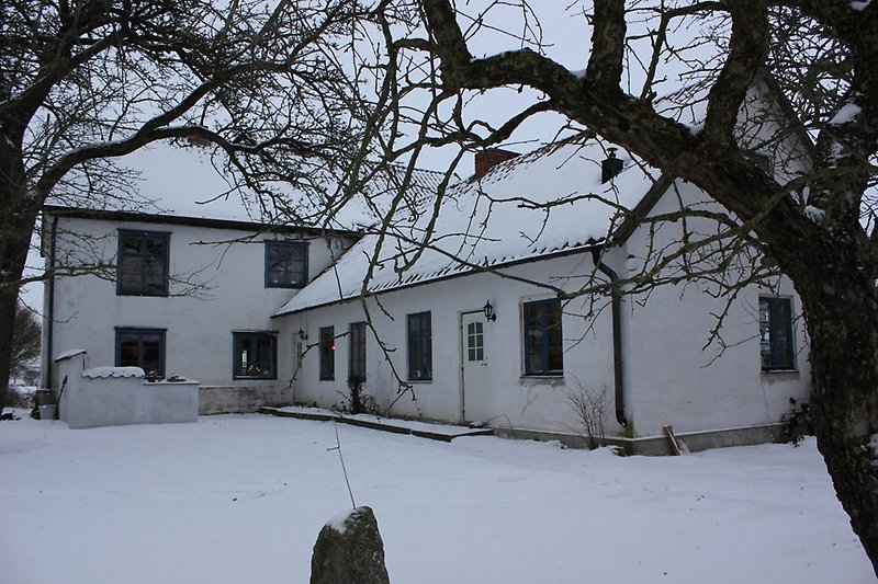 Ett stort vitt hus med blåa fönster och ett tak som är täckt med snön.
