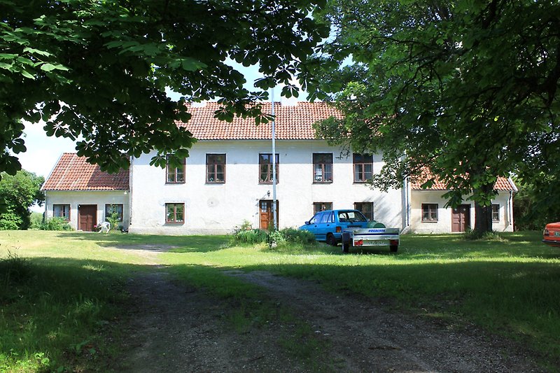 Ett vitt tvåvåningshus med bruna dörrar, bruna fönster och ett rött tegeltak.